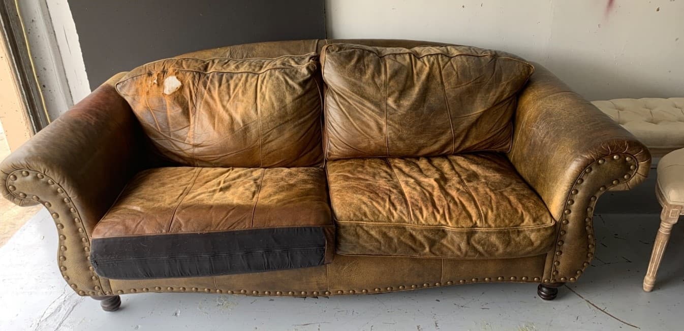 Heavily damaged brown leather sofa before restoration in Doylestown PA