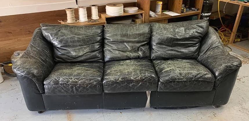 Black leather sofa with severe cat scratch damage before restoration in Philadelphia PA