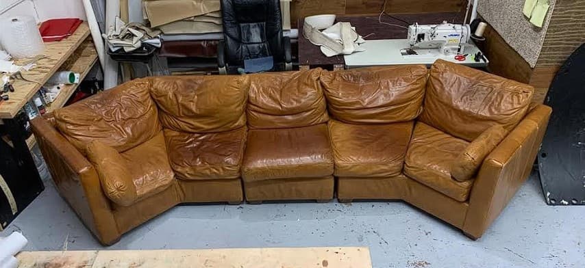 Large leather sectional before cushion refilling — collapsed and sagging cushions