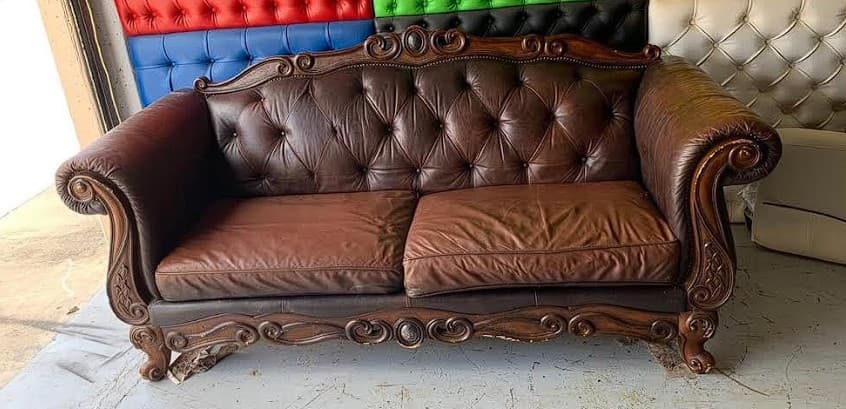 Ornate Chesterfield sofa before leather restoration — worn dark leather